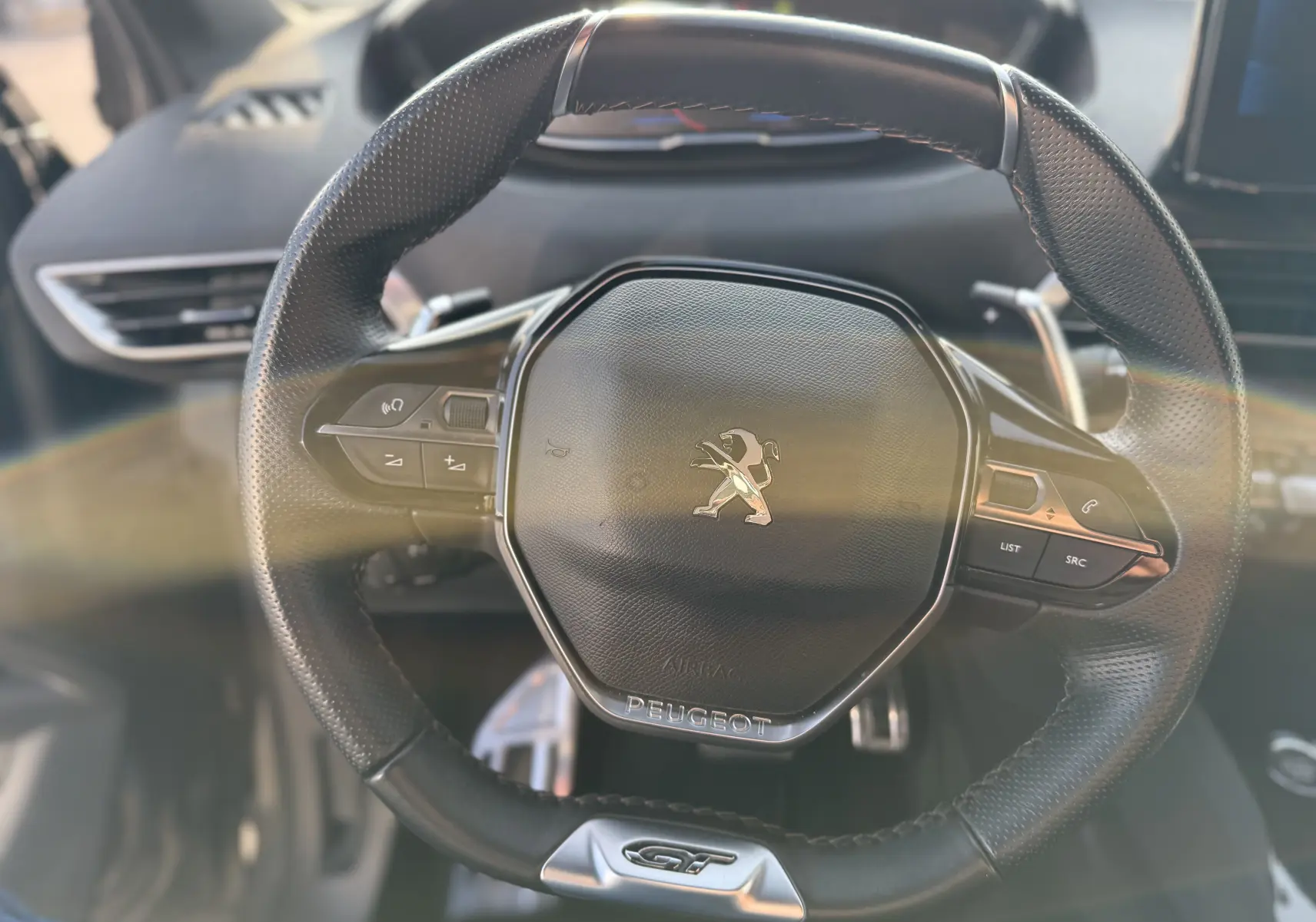 Vue rapprochée du volant cuir noir du Peugeot 3008 2022 avec logo lion et badge GT en bas.