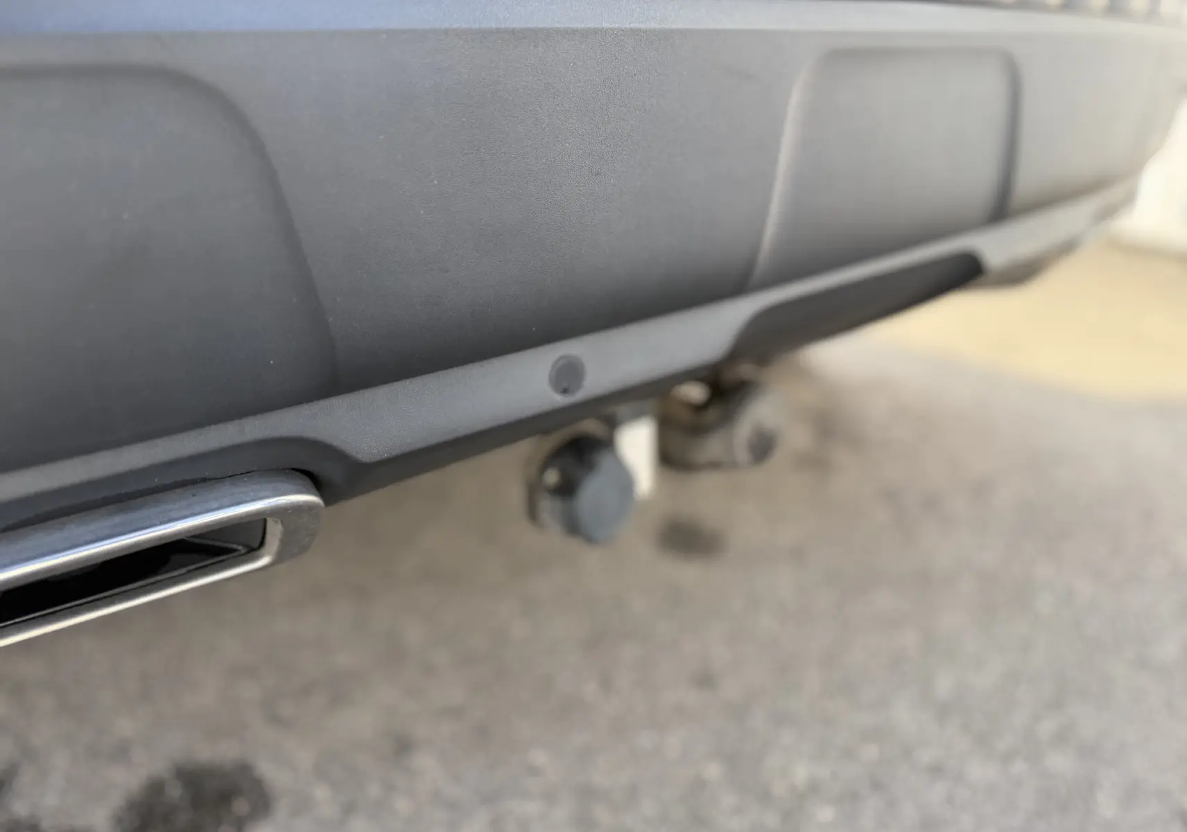 Gros plan sur l'attelage et l'échappement chromé du pare-chocs arrière gris du Peugeot 3008 2022.