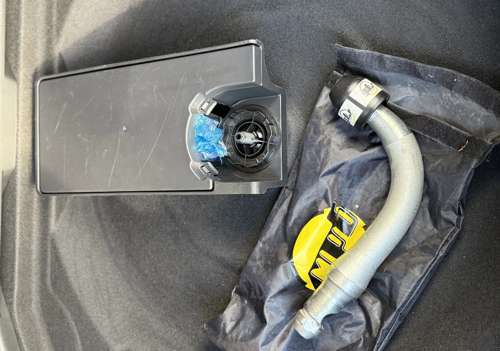 Détail de l'attelage amovible posé dans le coffre d'un Peugeot 3008 gris 2022, sur fond de moquette noire.