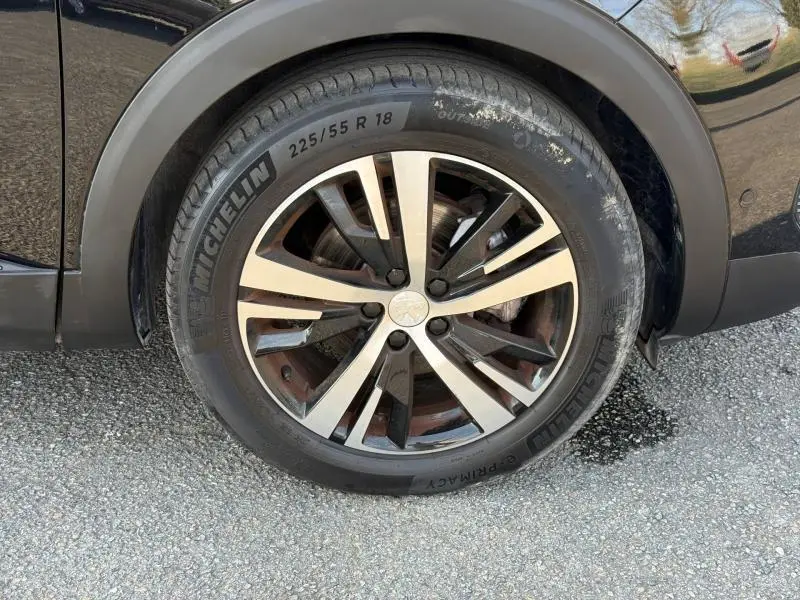 Gros plan sur la roue avant droite du Peugeot 3008 2024 en Bleu Célèbes avec jante alliage bicolore et pneu Michelin.