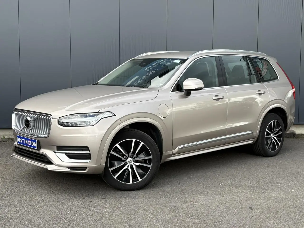 Volvo XC90 T8 hybride gris Dusk en 3/4 avant droit, avec jantes alliage noires et contour chromé des vitres.