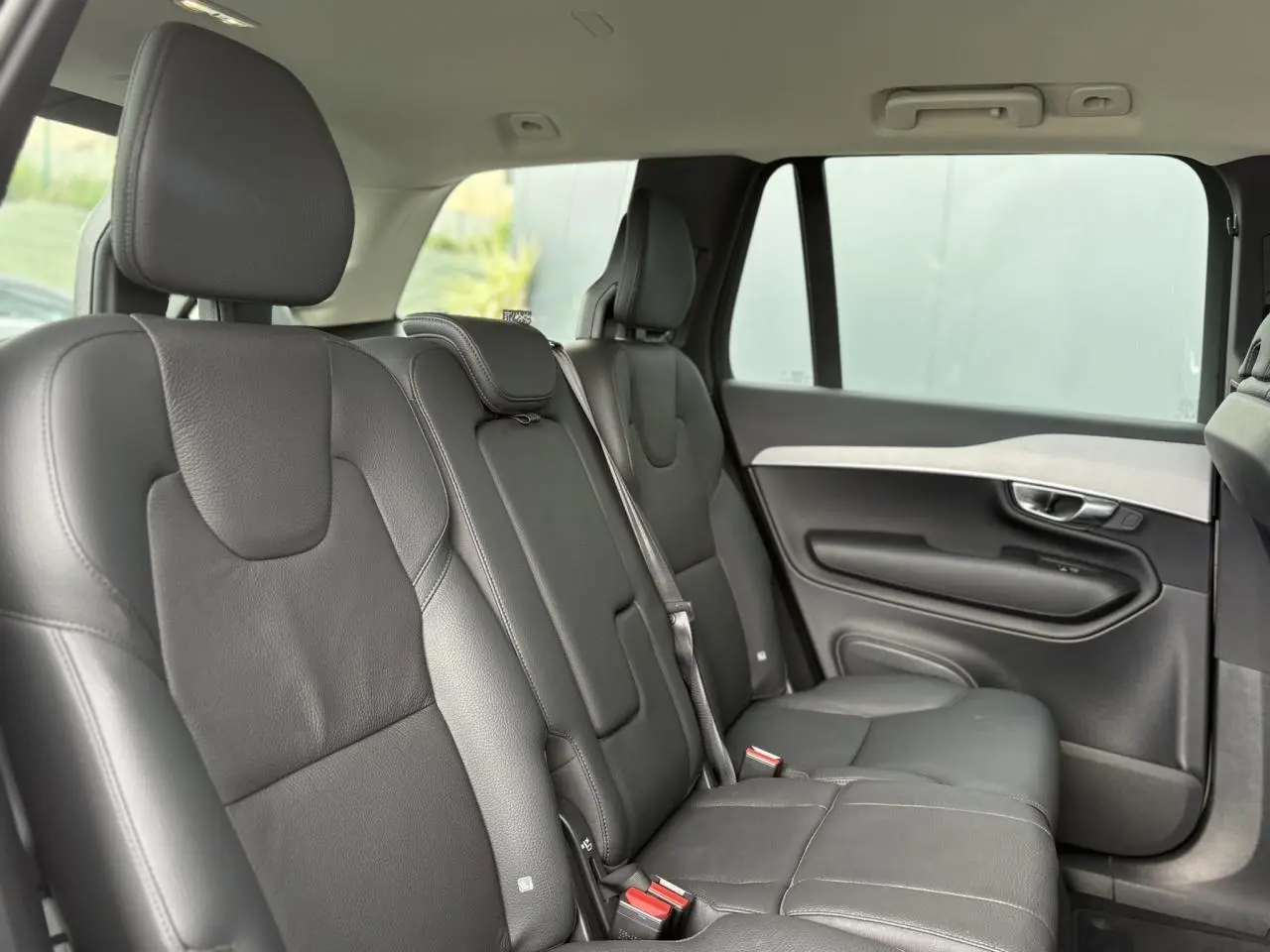 Vue intérieure côté droit des sièges arrière en cuir noir du Volvo XC90 T8 AWD 2024, avec appuie-têtes et ceintures visibles.