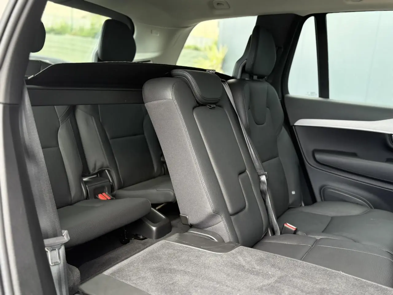 Vue intérieure côté droit des sièges arrière noirs en cuir du Volvo XC90 T8 AWD PHEV 2024 avec troisième rangée rabattue.