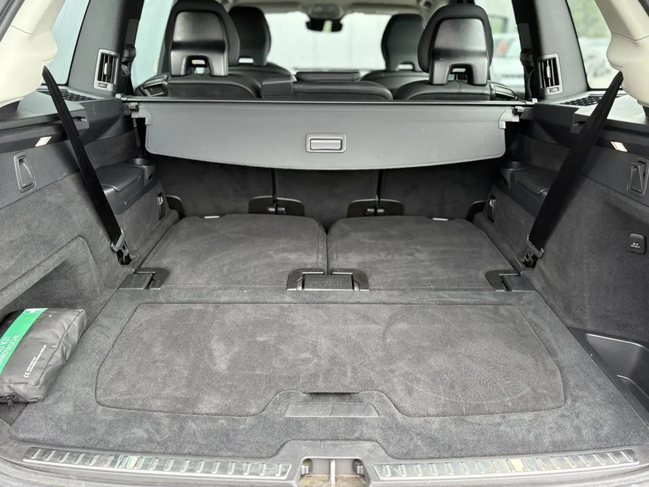 Coffre spacieux du Volvo XC90 gris Dusk, sièges arrière rabattus et cache-bagages déployé, vue arrière intérieure.
