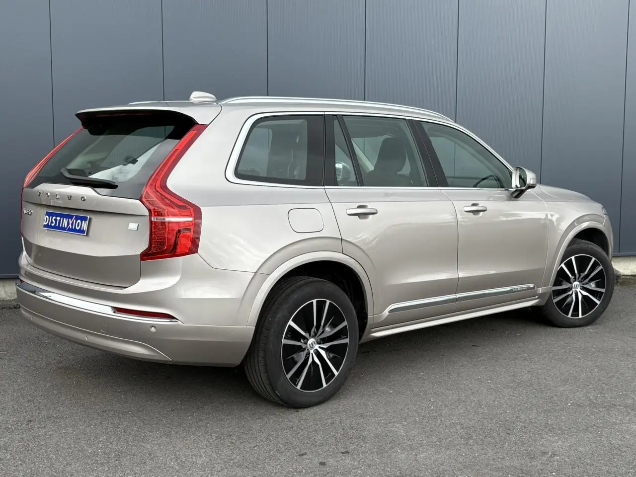 Vue 3/4 arrière droite du Volvo XC90 T8 hybride gris Dusk avec jantes alliage noires et chrome autour des vitres.