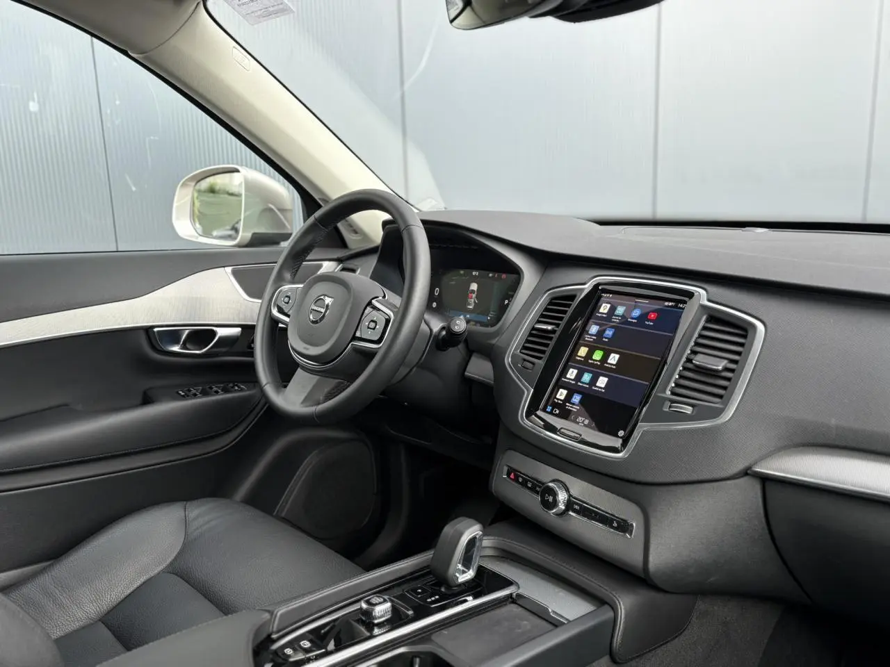 Vue intérieure côté conducteur du Volvo XC90 gris Dusk 2024, avec tableau de bord digital et écran tactile central.