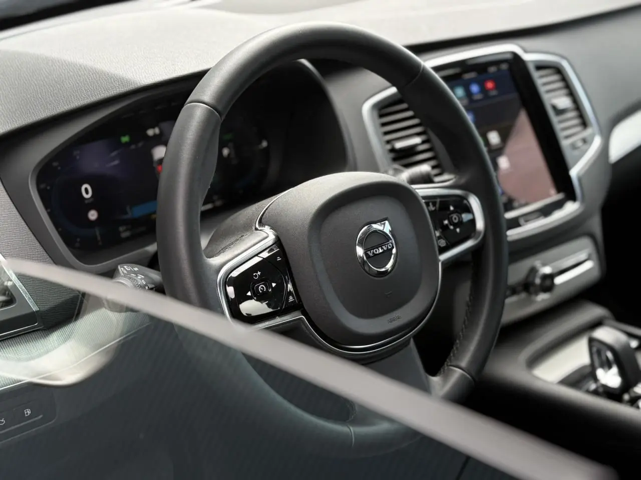 Vue rapprochée du volant noir et du tableau de bord digital du Volvo XC90 2024, intérieur moderne et épuré.
