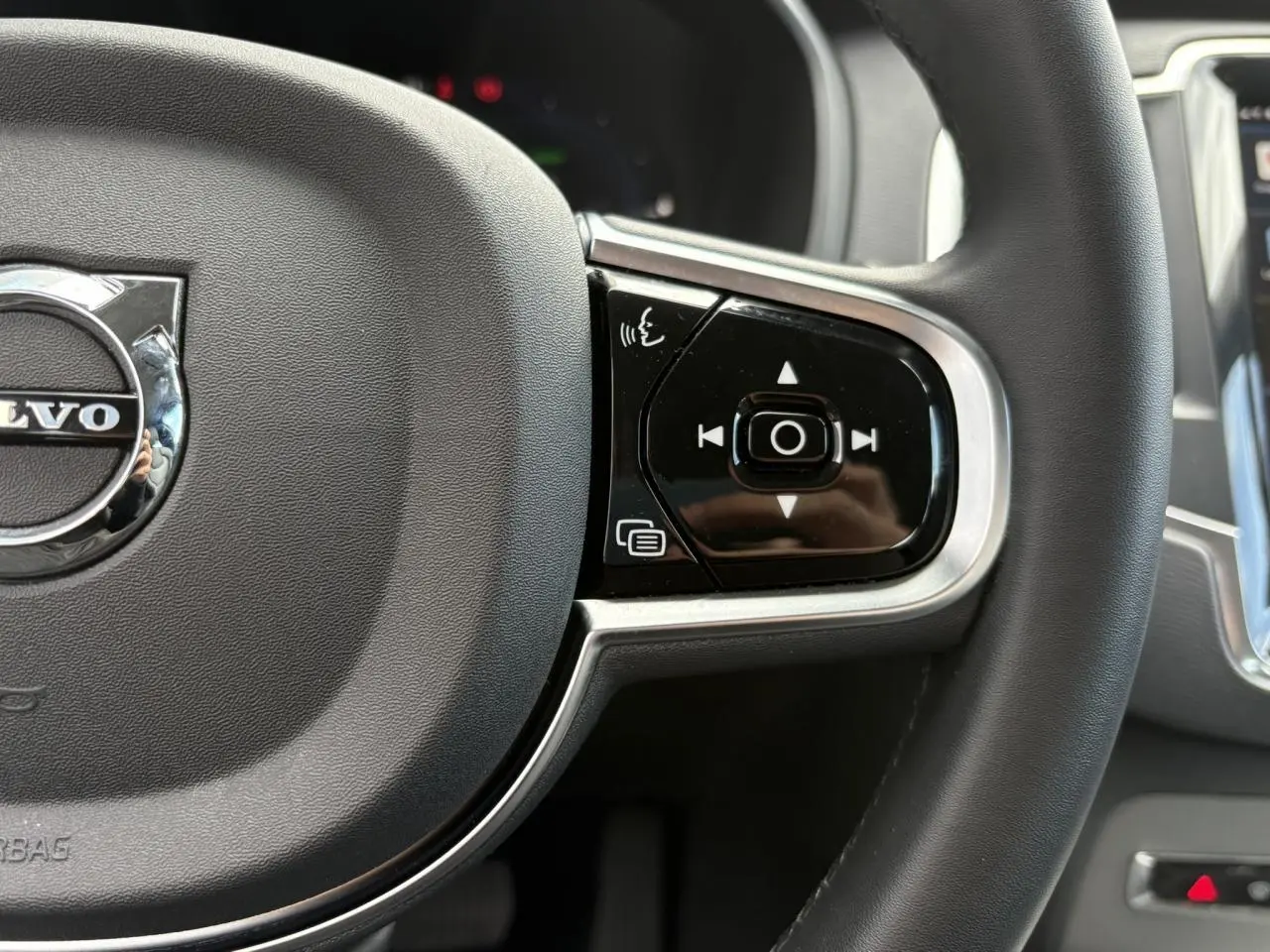 Gros plan sur la partie droite du volant noir du Volvo XC90 2024 avec commandes vocales et multimédia intégrées.