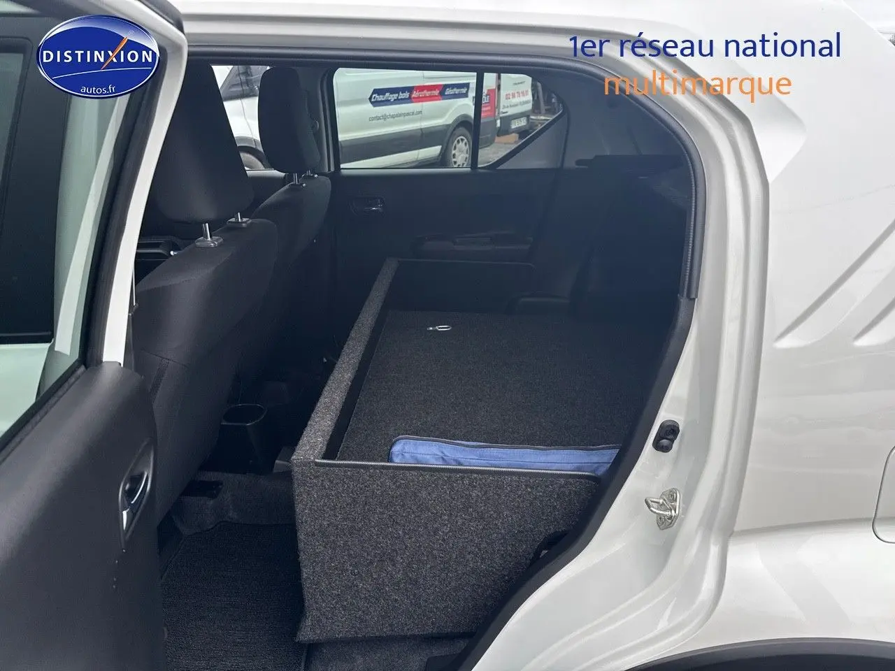Vue intérieure côté gauche de la Suzuki Ignis blanche 2023 avec banquette arrière rabattue et rangement installé.