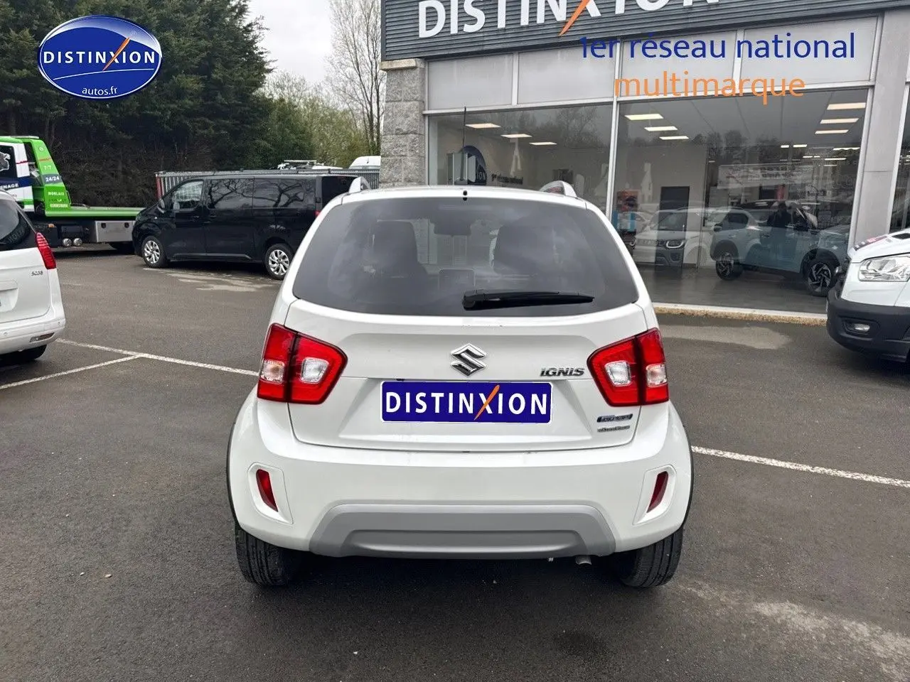 Vue arrière d'une Suzuki Ignis blanche Pure White Pearl métallisé garée devant un showroom Distinxion.