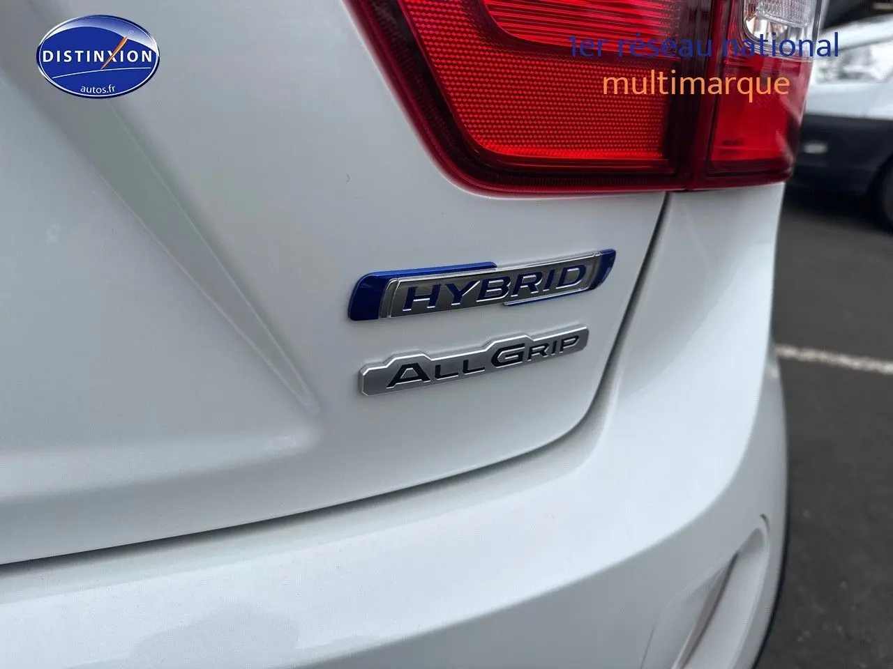 Gros plan sur l'arrière droit blanc nacré d'une Suzuki Ignis 2023 avec badges Hybrid et AllGrip visibles.