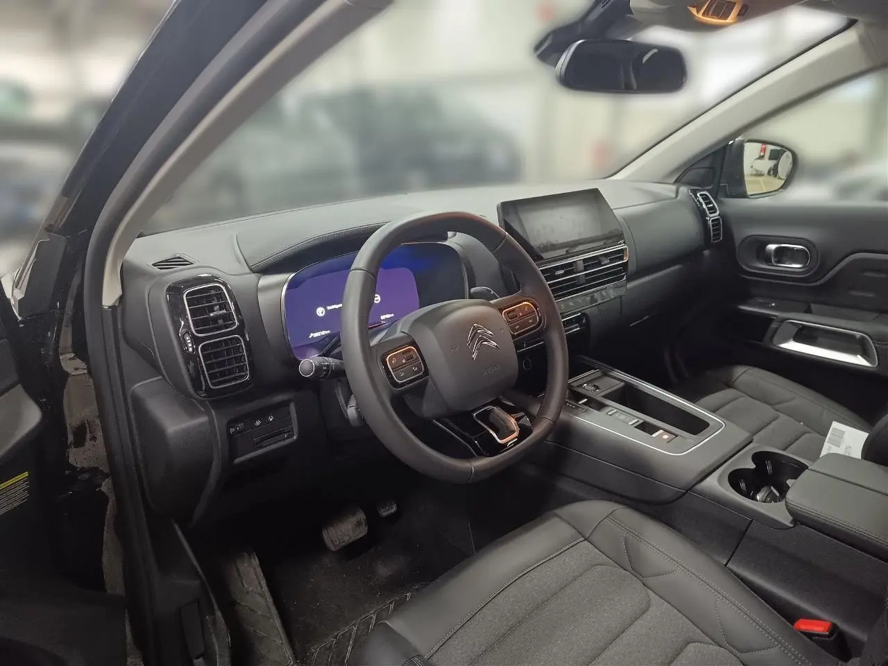 Vue intérieure côté conducteur du Citroën C5 Aircross Hybrid noir Perla, avec tableau de bord numérique et volant multifonction.