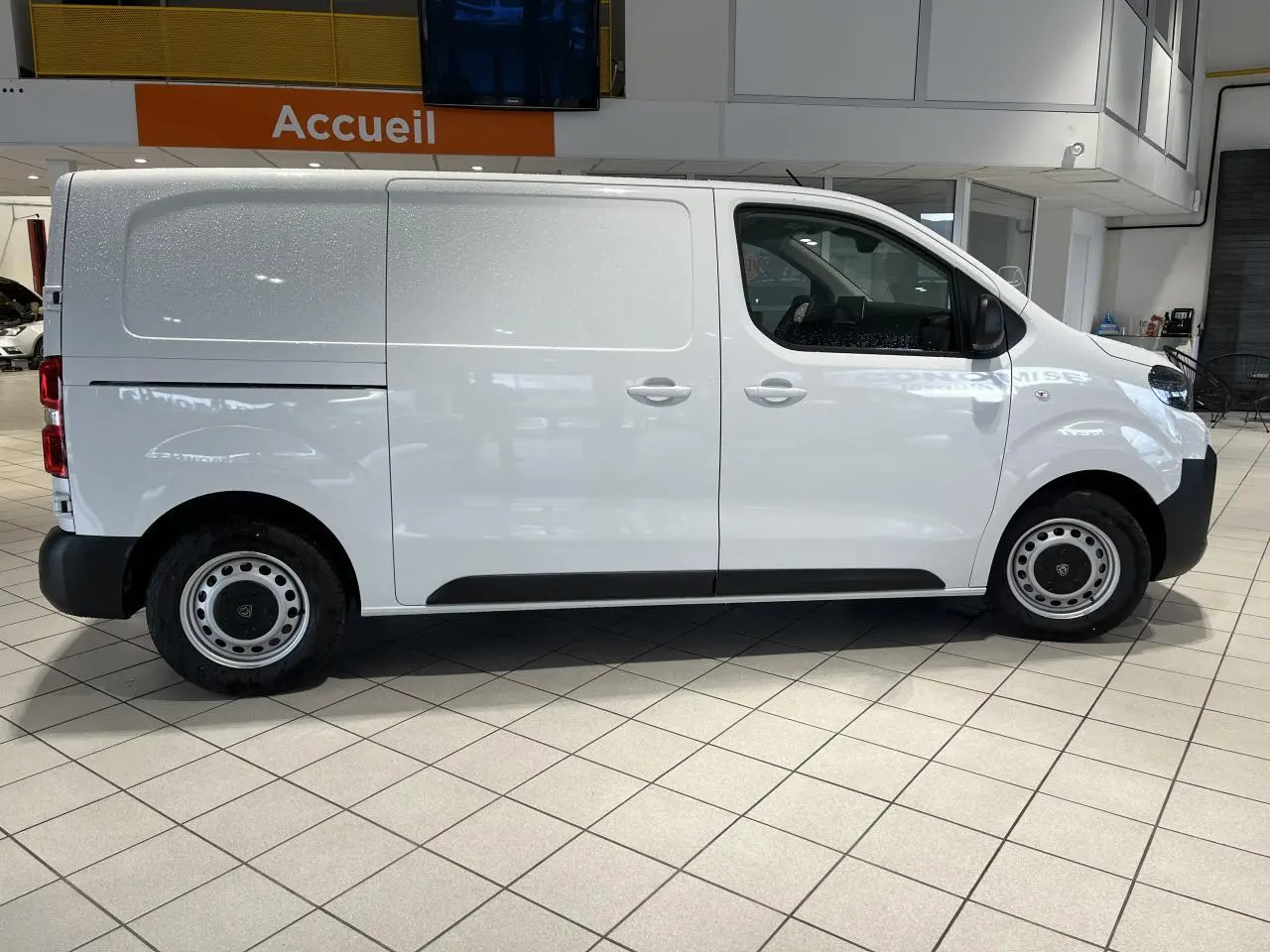 Vue latérale droite d'un Peugeot Expert Fourgon blanc 2024 en intérieur, avec jantes acier et portes coulissantes.