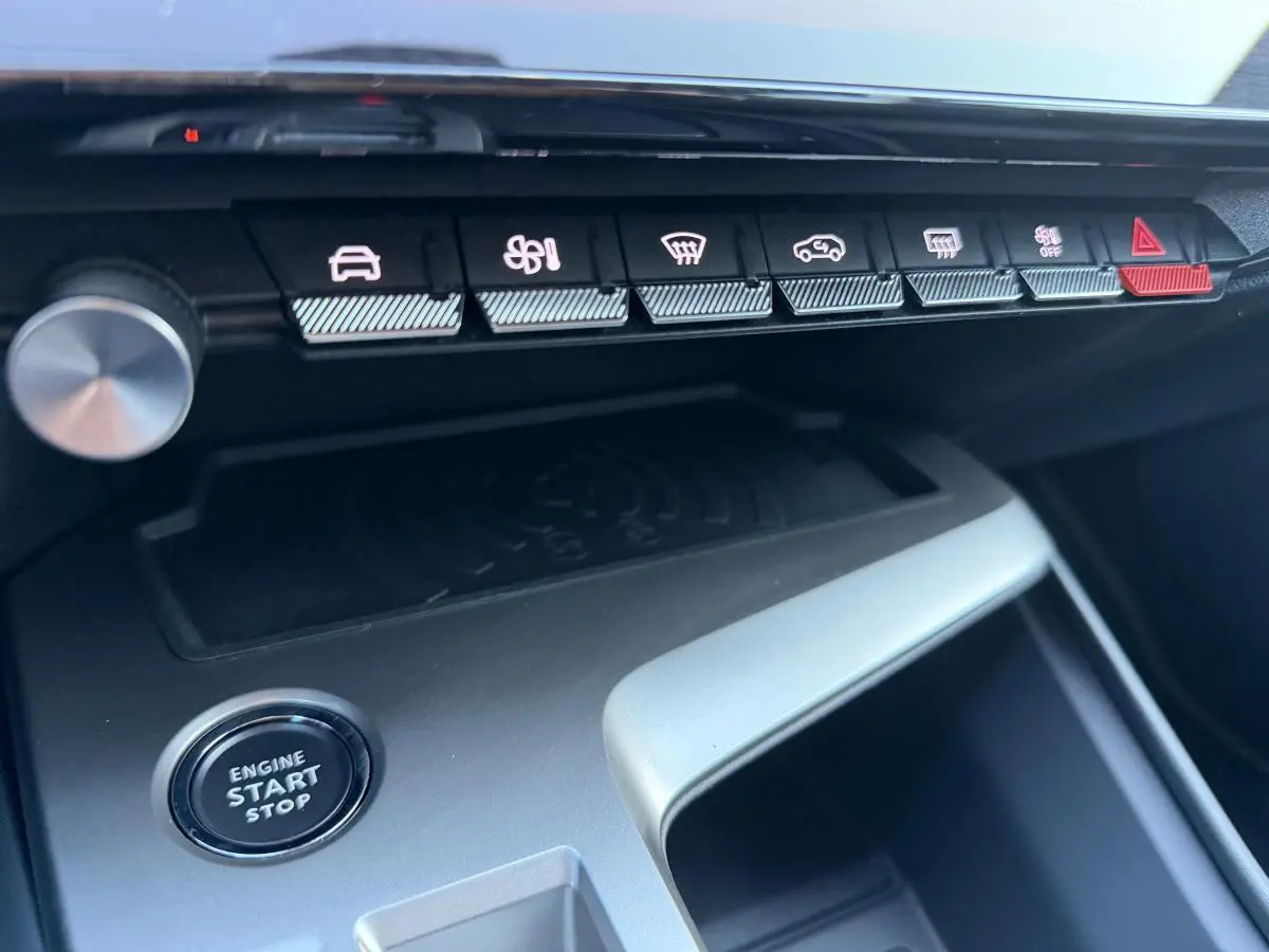 Gros plan sur la console centrale de la Peugeot 308 2024 noire, avec boutons de commande et bouton start/stop visible.