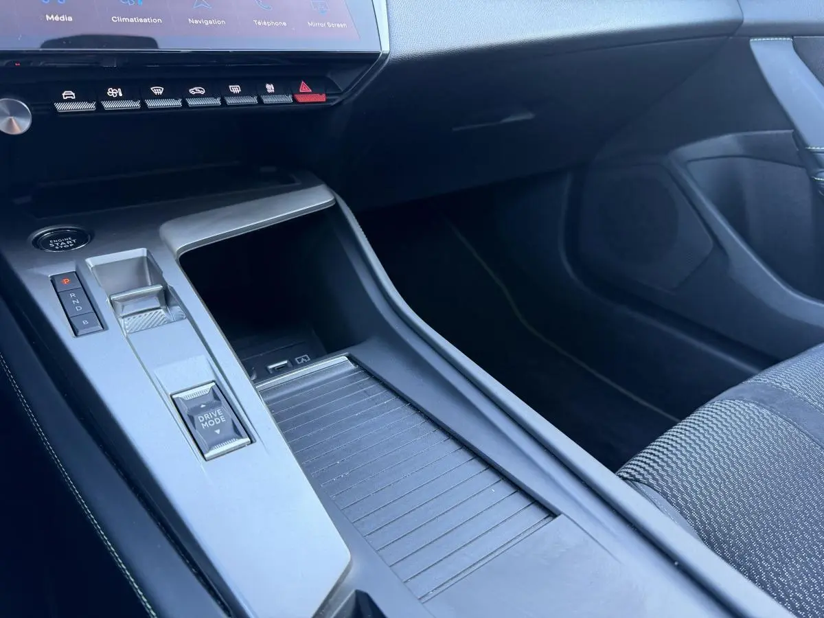 Gros plan sur la console centrale grise et noire de la Peugeot 308 2024 avec commandes Drive Mode et bouton start.