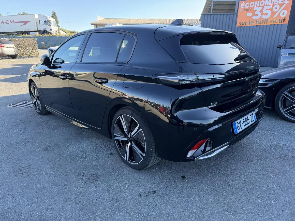Peugeot 308 noire vue en 3/4 arrière droit, avec jantes alliage 18'' et feux arrière à signature lumineuse dynamique.