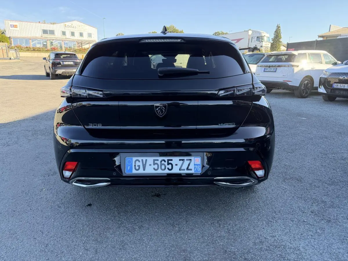 Vue arrière d'une Peugeot 308 noire métallisée 2024 avec feux arrière à signature lumineuse griffe à griffe.