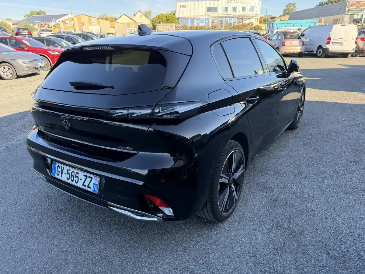 Vue 3/4 arrière droite d'une Peugeot 308 noire métallisée avec feux arrière à signature lumineuse griffe à griffe.