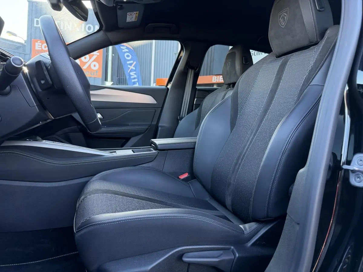 Vue intérieure côté conducteur de la Peugeot 308 2024 noire, sièges tri matières avec logo Lion brodé sur appuie-tête.