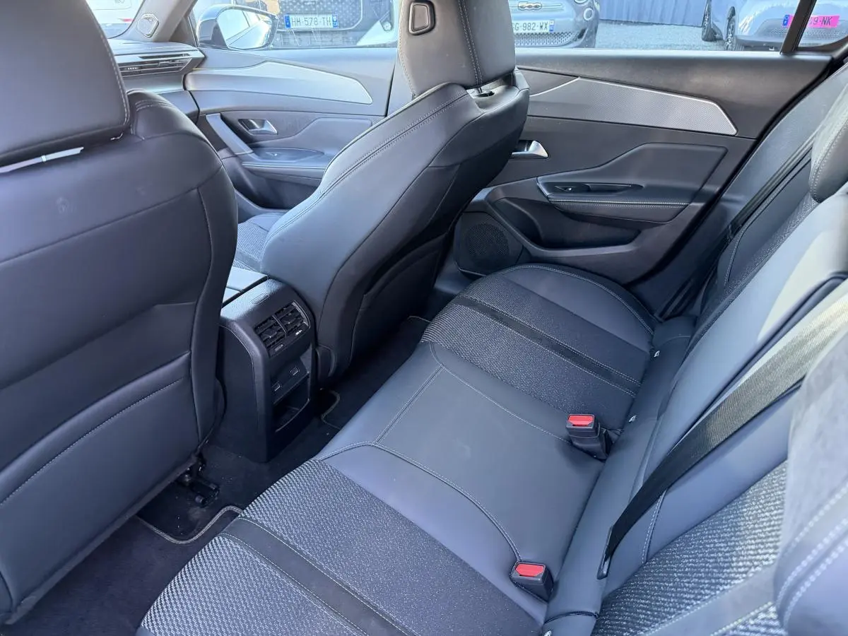 Vue arrière intérieure de la Peugeot 308 2024, sièges noirs en tissu et TEP avec prises USB C et aérateurs centraux.