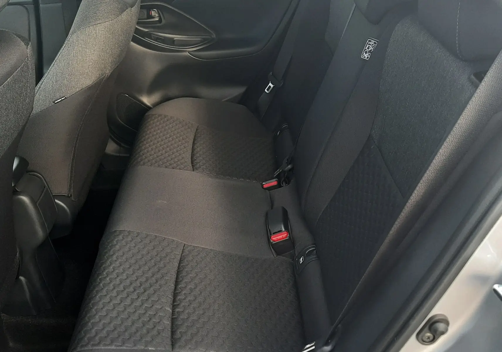 Vue intérieure côté droit des sièges arrière en tissu gris foncé du Toyota Yaris Cross 130H Design gris minéral 2025.