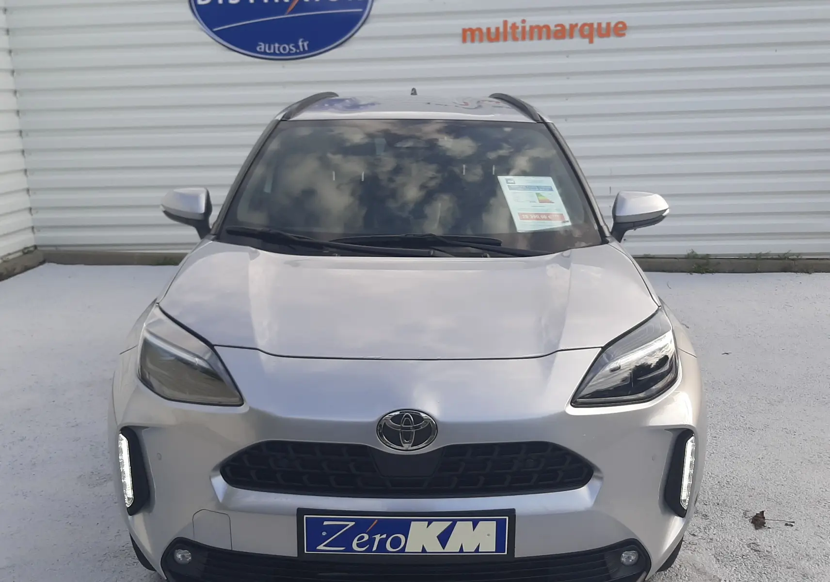 Vue de face d'une Toyota Yaris Cross 130H Design gris minéral avec feux LED et plaque Zéro KM visible.