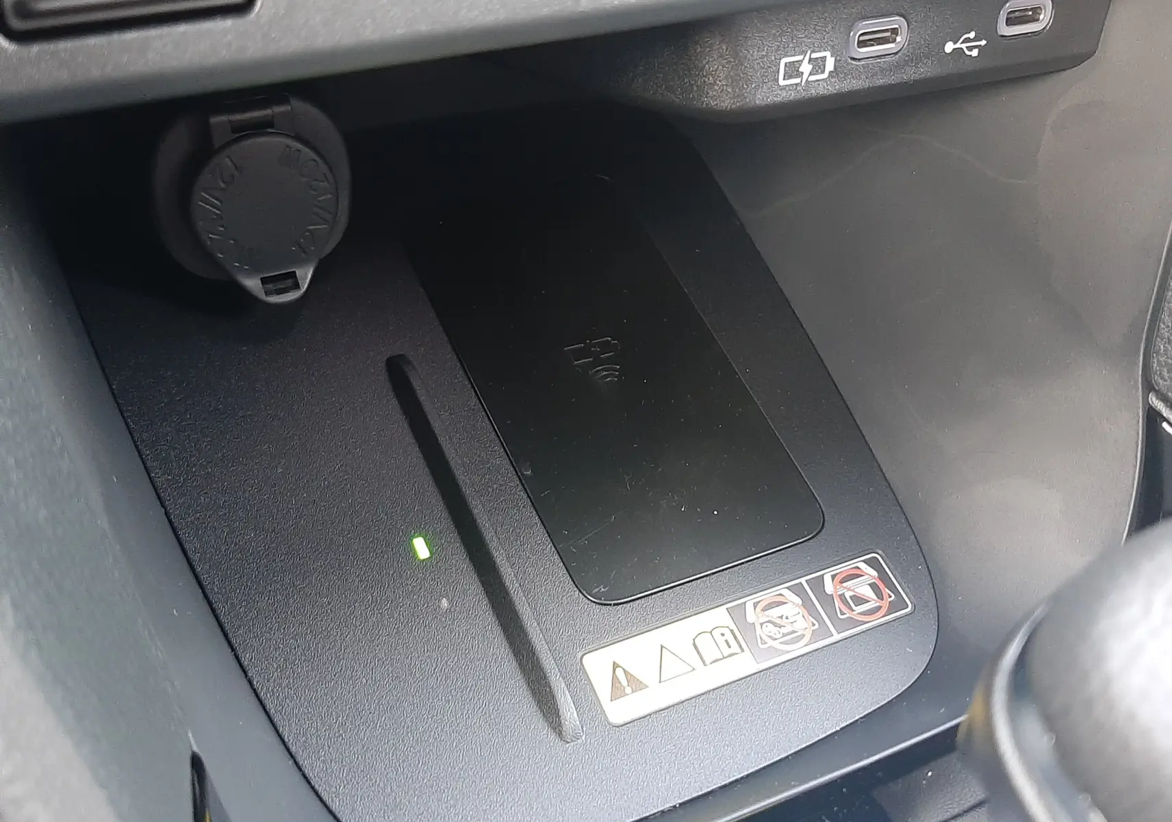 Gros plan sur la zone de recharge sans fil et ports USB dans l'habitacle gris de la Toyota Yaris Cross 130H Design 2025.
