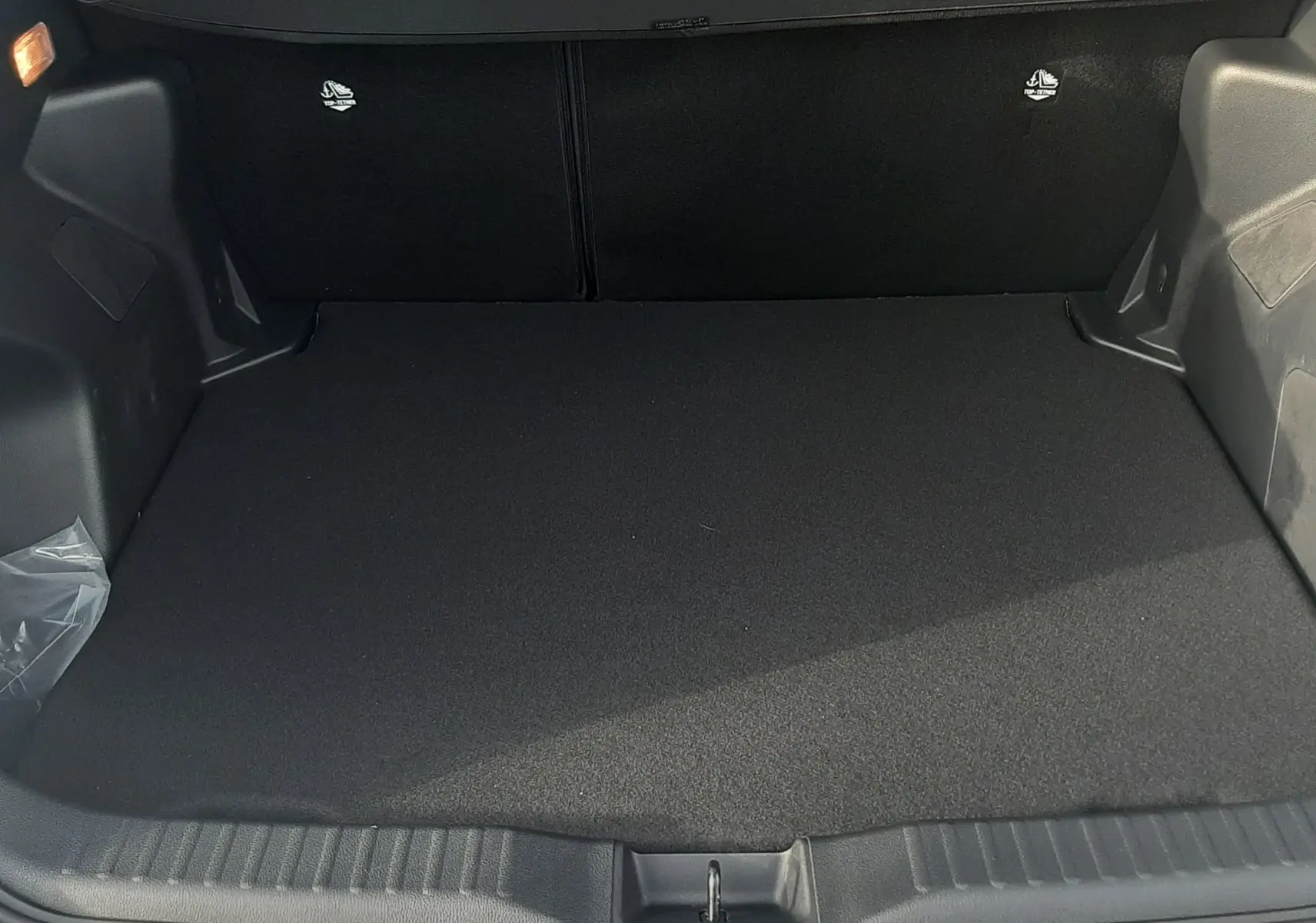 Coffre ouvert de la Toyota Yaris Cross 130H Design gris minéral, montrant l'espace de chargement vide et le seuil de coffre.