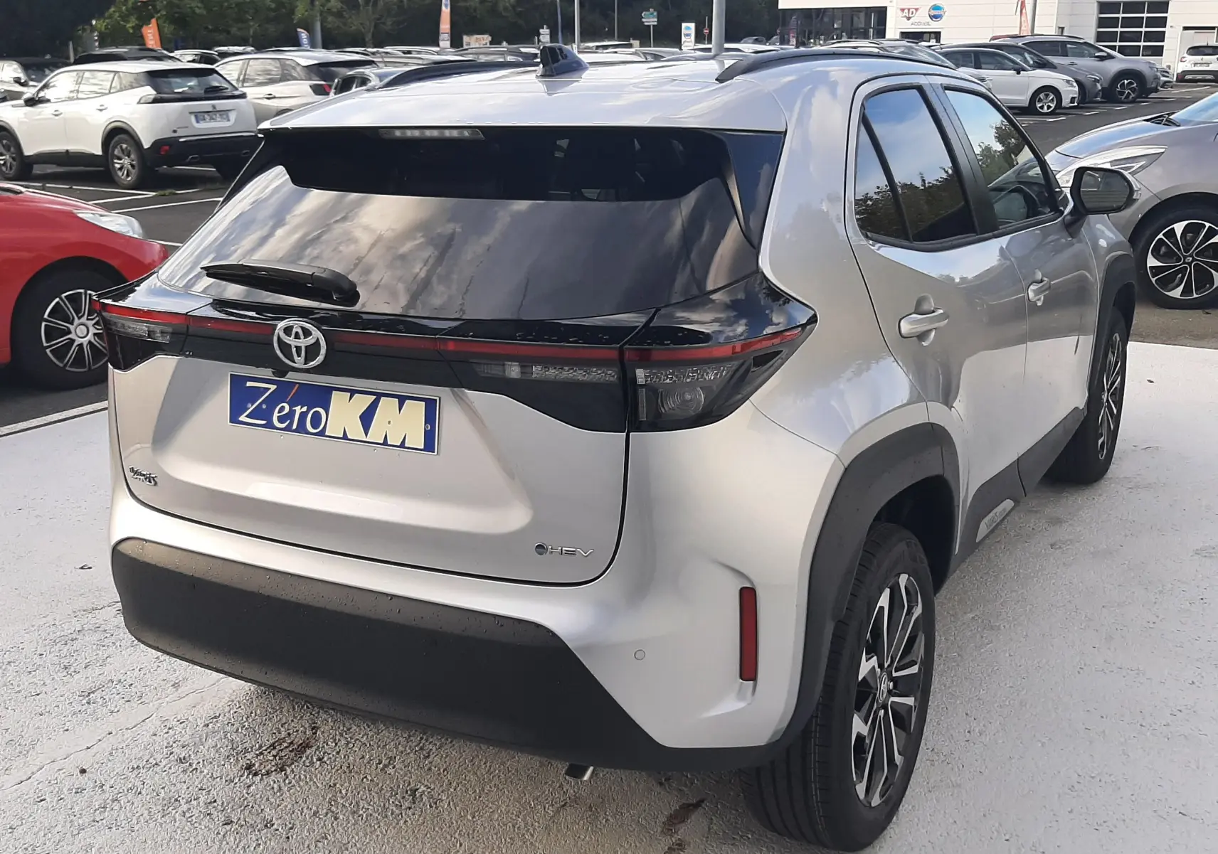Toyota Yaris Cross 130H Design gris minéral vue 3/4 arrière droit avec toit noir et feux arrière LED distinctifs.