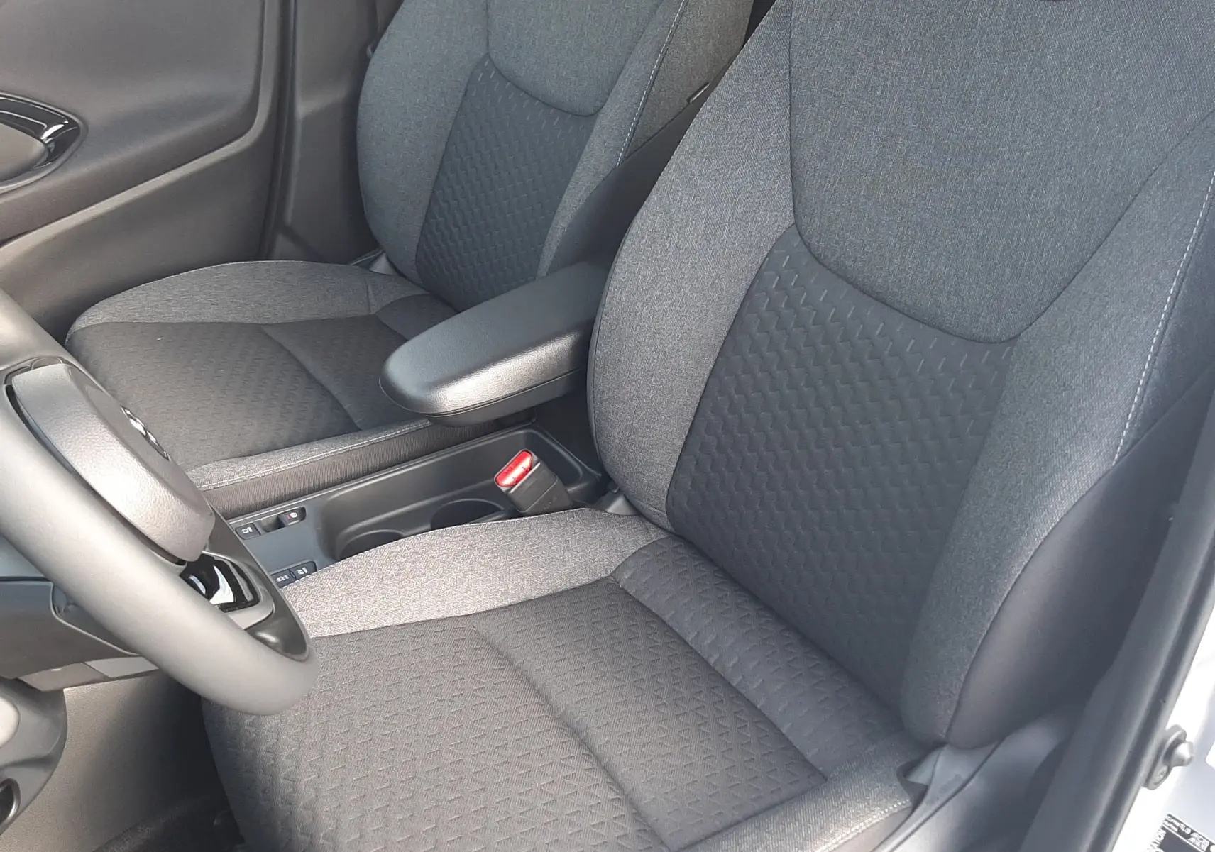 Vue intérieure rapprochée des sièges avant en tissu gris foncé de la Toyota Yaris Cross 130H Design 2025.
