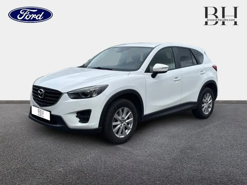 Vue 3/4 avant droite d'un Mazda CX-5 blanc nacré avec calandre noire et jantes alliage sur fond neutre.