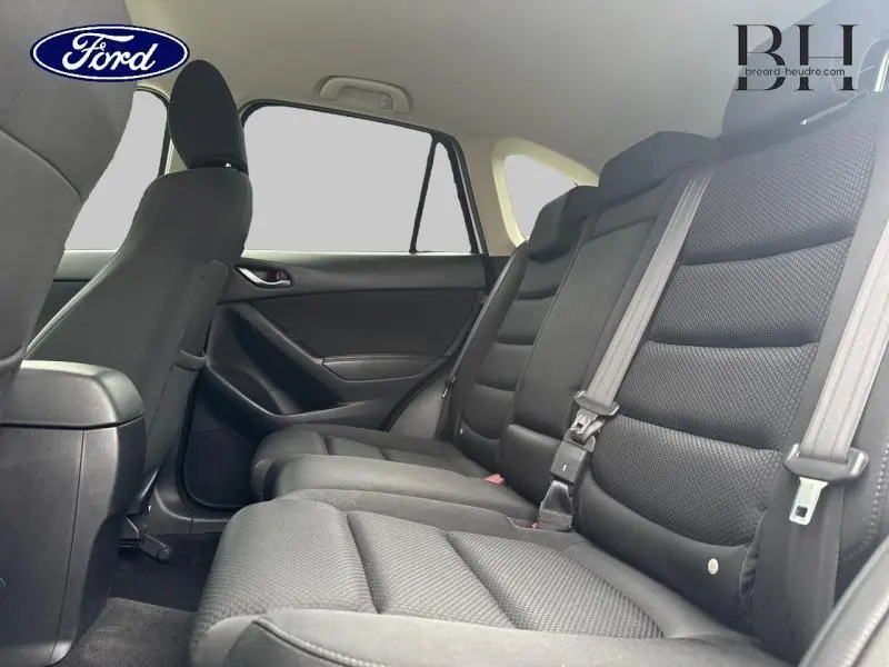 Vue intérieure sur les sièges arrière noirs d'un Mazda CX-5 2016, mettant en valeur l'espace et la finition tissu.