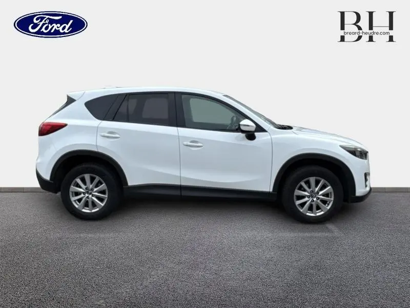 Profil côté gauche d'un Mazda CX-5 blanc nacré, version 2.2 SKYACTIV-D 150 Dynamique 4x2 de 2016, sur fond neutre.