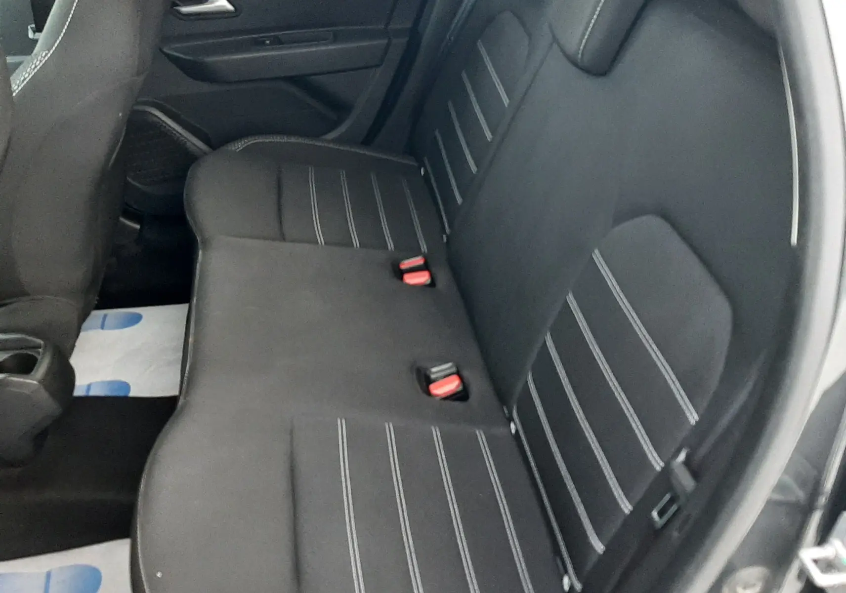 Vue intérieure côté droit montrant la banquette arrière en tissu noir avec surpiqûres blanches du Dacia Duster gris Cassiopée.