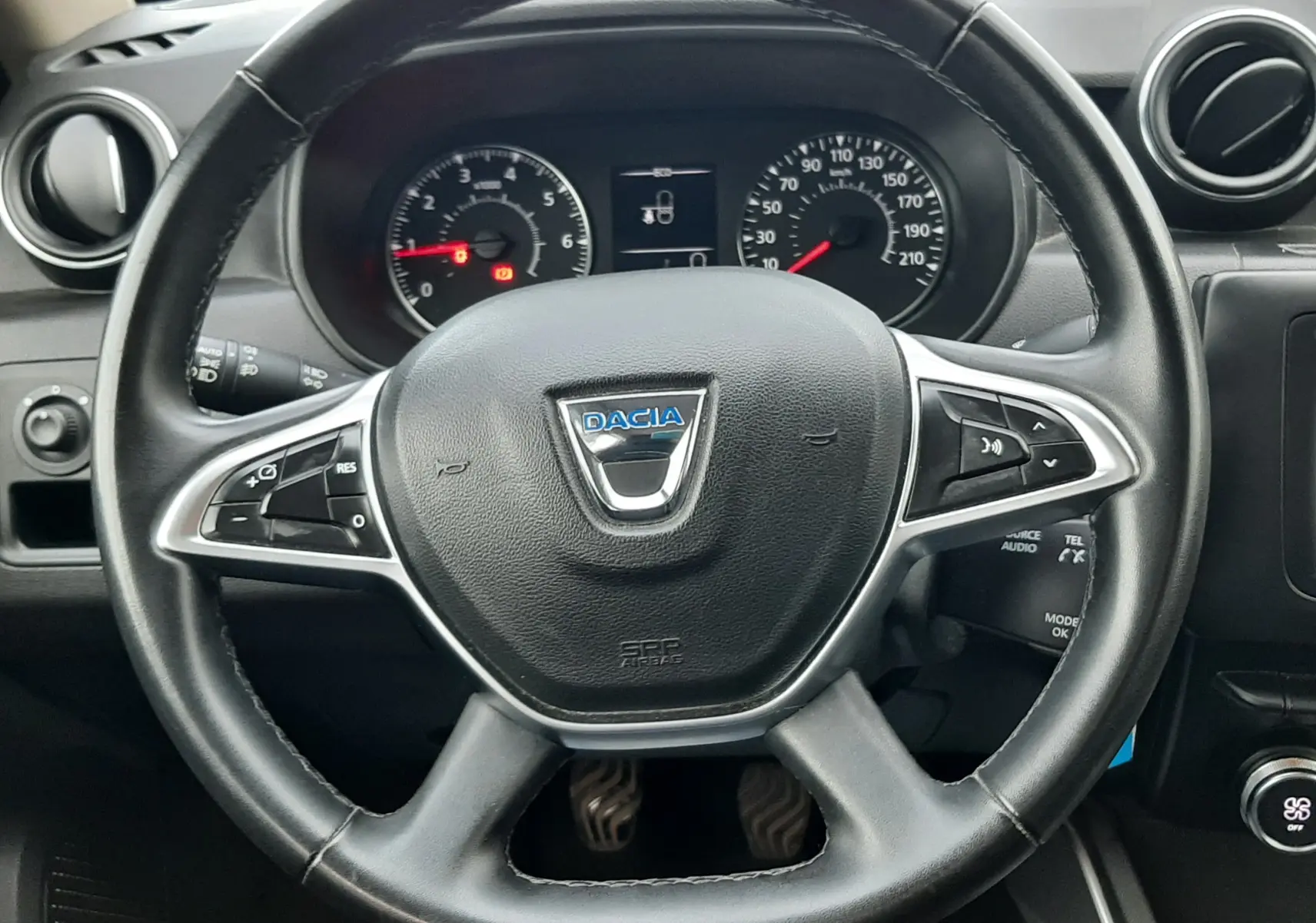 Vue centrée sur le volant noir du Dacia Duster 2019 avec tableau de bord et commandes visibles en arrière-plan.