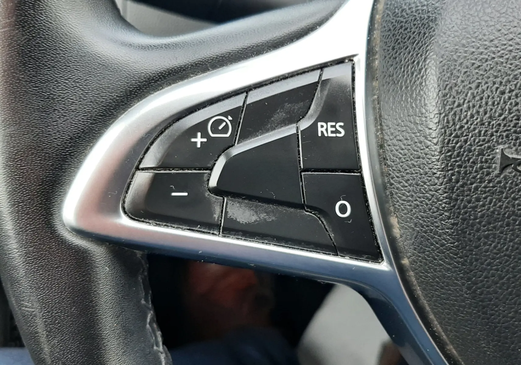 Gros plan sur les commandes de régulateur de vitesse au volant noir du Dacia Duster gris Cassiopée 2019.