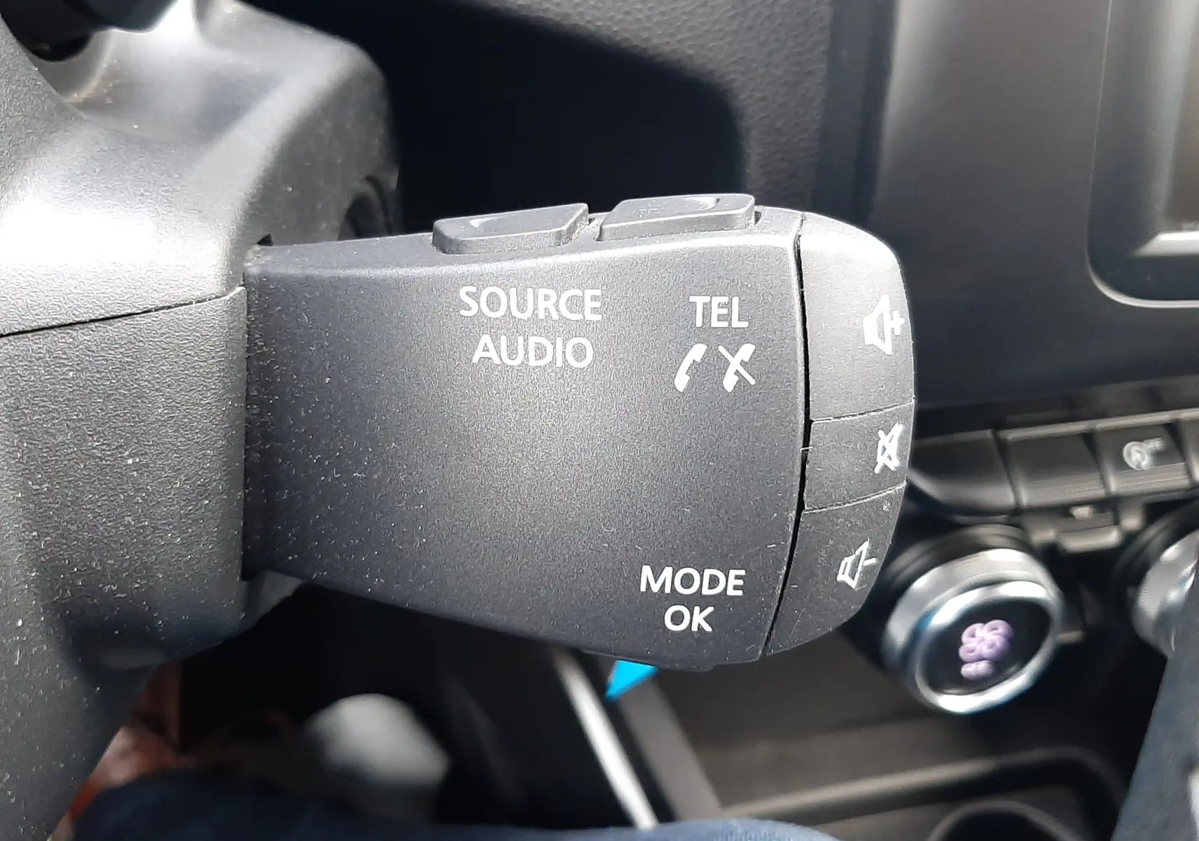 Gros plan sur la commande audio au volant noir dans l’habitacle du Dacia Duster gris Cassiopée 2019.