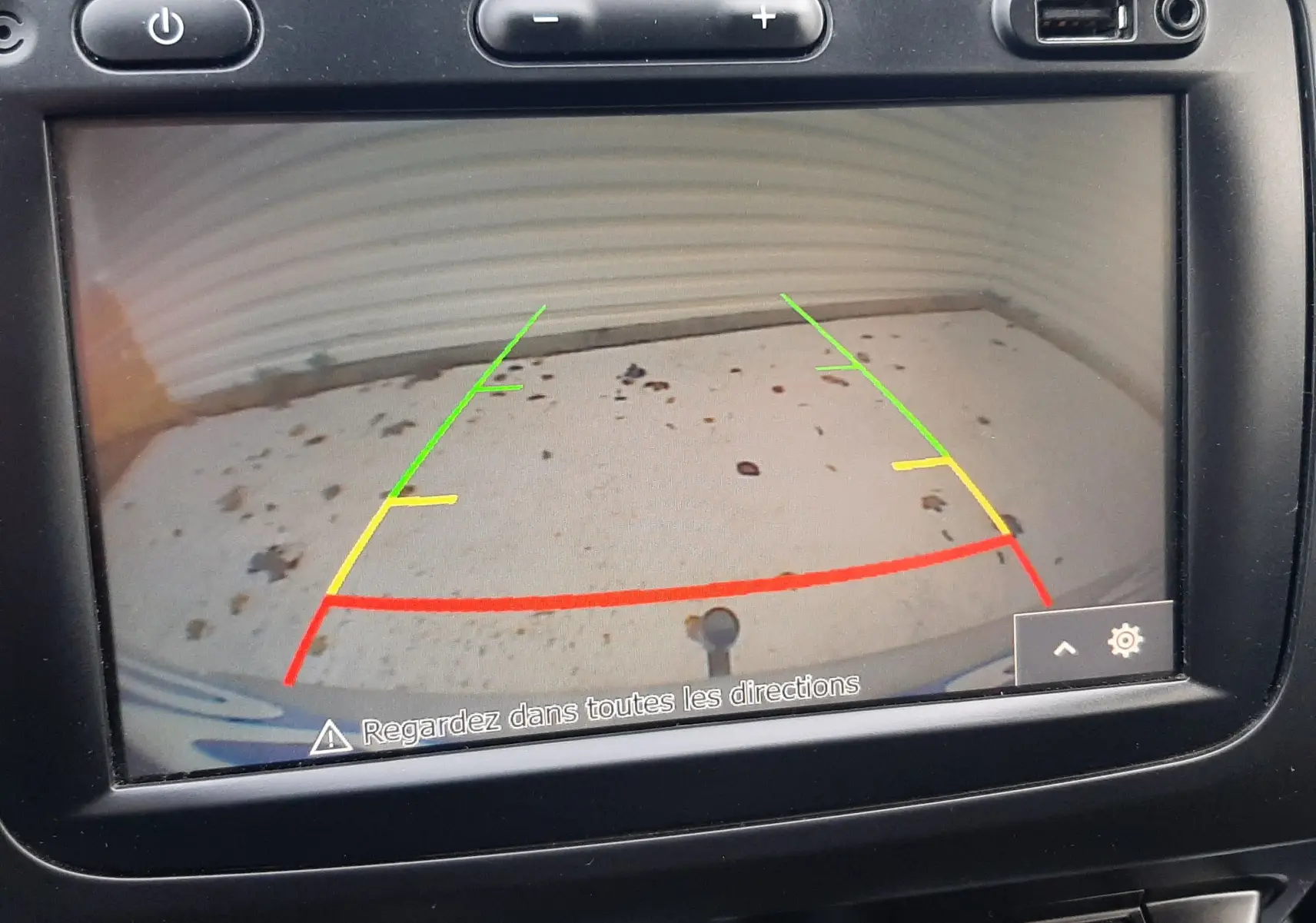 Écran de caméra de recul du Dacia Duster 2019 montrant le sol avec lignes de guidage colorées dans l'habitacle noir.