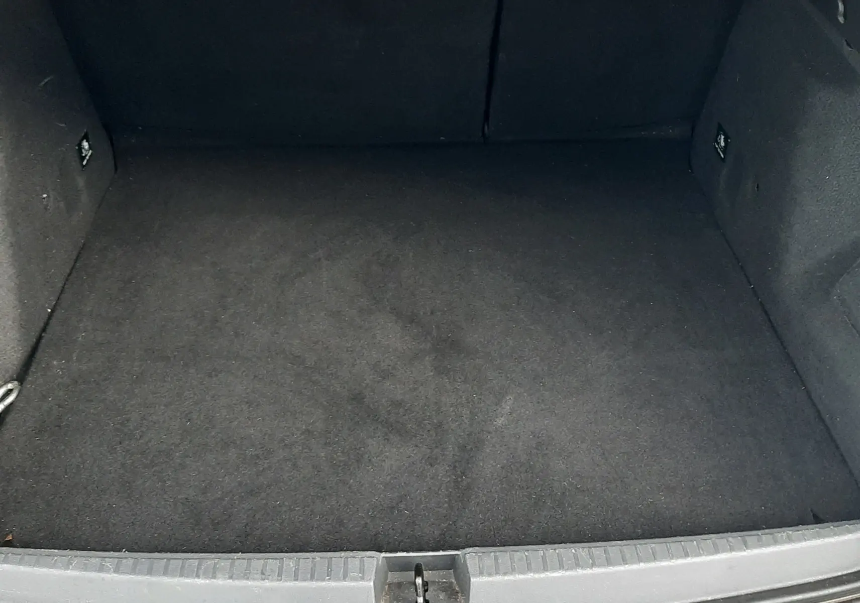 Coffre ouvert du Dacia Duster gris Cassiopée, vue plongeante sur l’espace de rangement vide et propre.