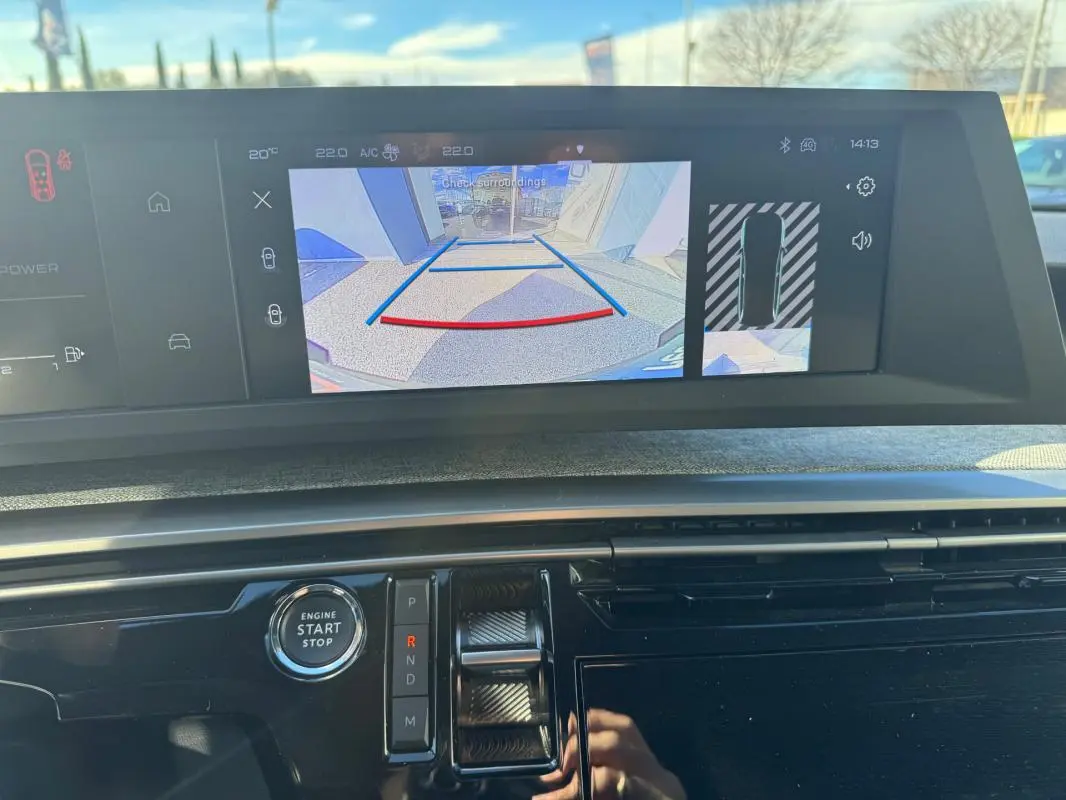 Vue rapprochée du tableau de bord du Peugeot 5008 Hybrid gris, avec écran de caméra de recul et commande de boîte auto.