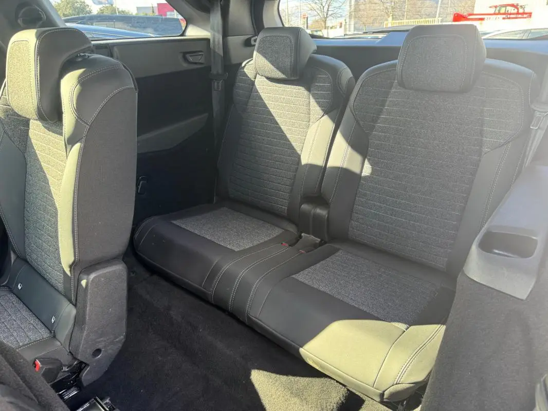 Vue intérieure arrière montrant la troisième rangée de sièges gris du Peugeot 5008 Hybrid 145 e-DCS6 Allure 2025.