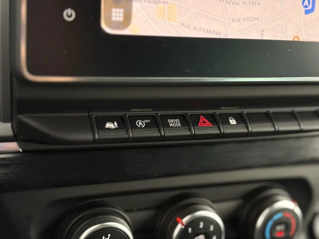 Gros plan sur les commandes centrales noires du tableau de bord du Nissan Primastar 2025, avec écran tactile visible en haut.