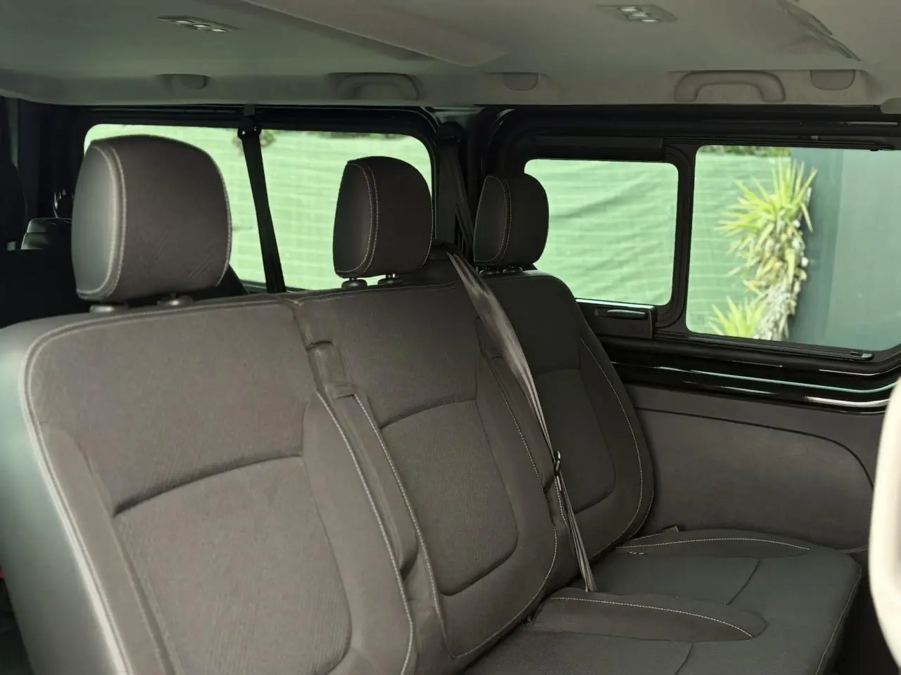 Vue intérieure côté droit sur les sièges noirs du Nissan Primastar 2025 avec vitres latérales coulissantes ouvertes.