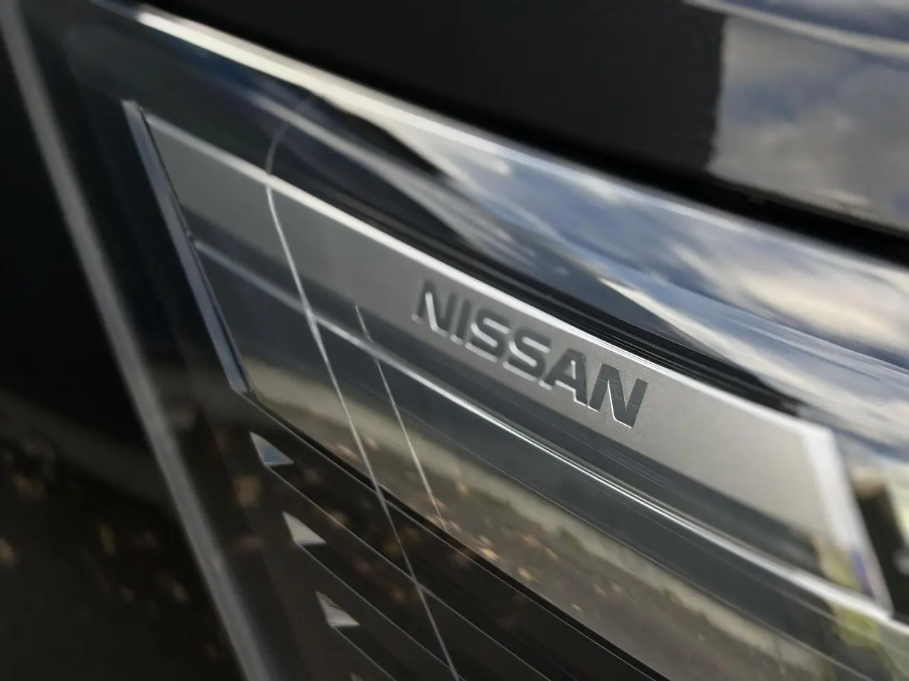 Gros plan sur la calandre noire métallisée du Nissan Primastar avec le logo Nissan en relief argenté.