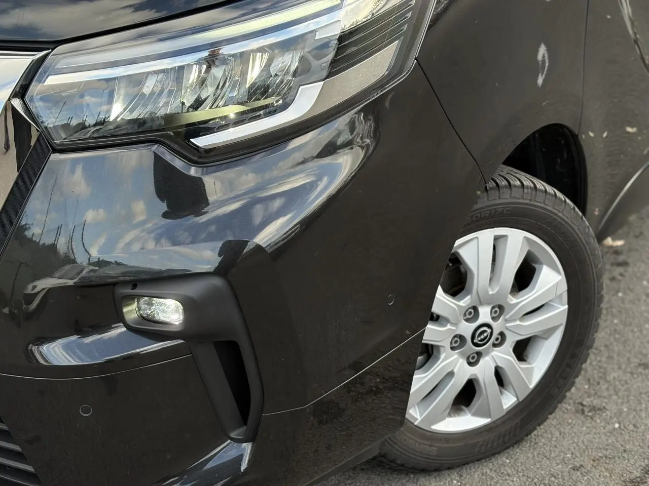 Gros plan sur l'avant droit noir métallisé du Nissan Primastar 2025 avec phare LED et jante alliage 17 pouces.