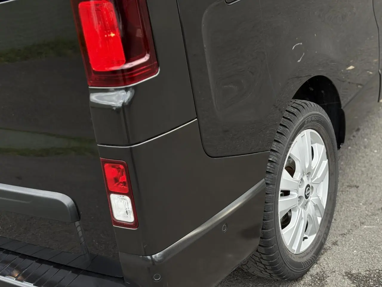 Gros plan sur l'arrière droit noir métallisé du Nissan Primastar 2025, avec feu arrière et jante alliage 17 pouces.