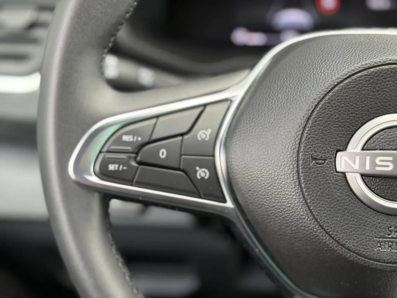 Gros plan sur le volant noir du Nissan Primastar 2025 avec commandes intégrées au volant côté gauche.