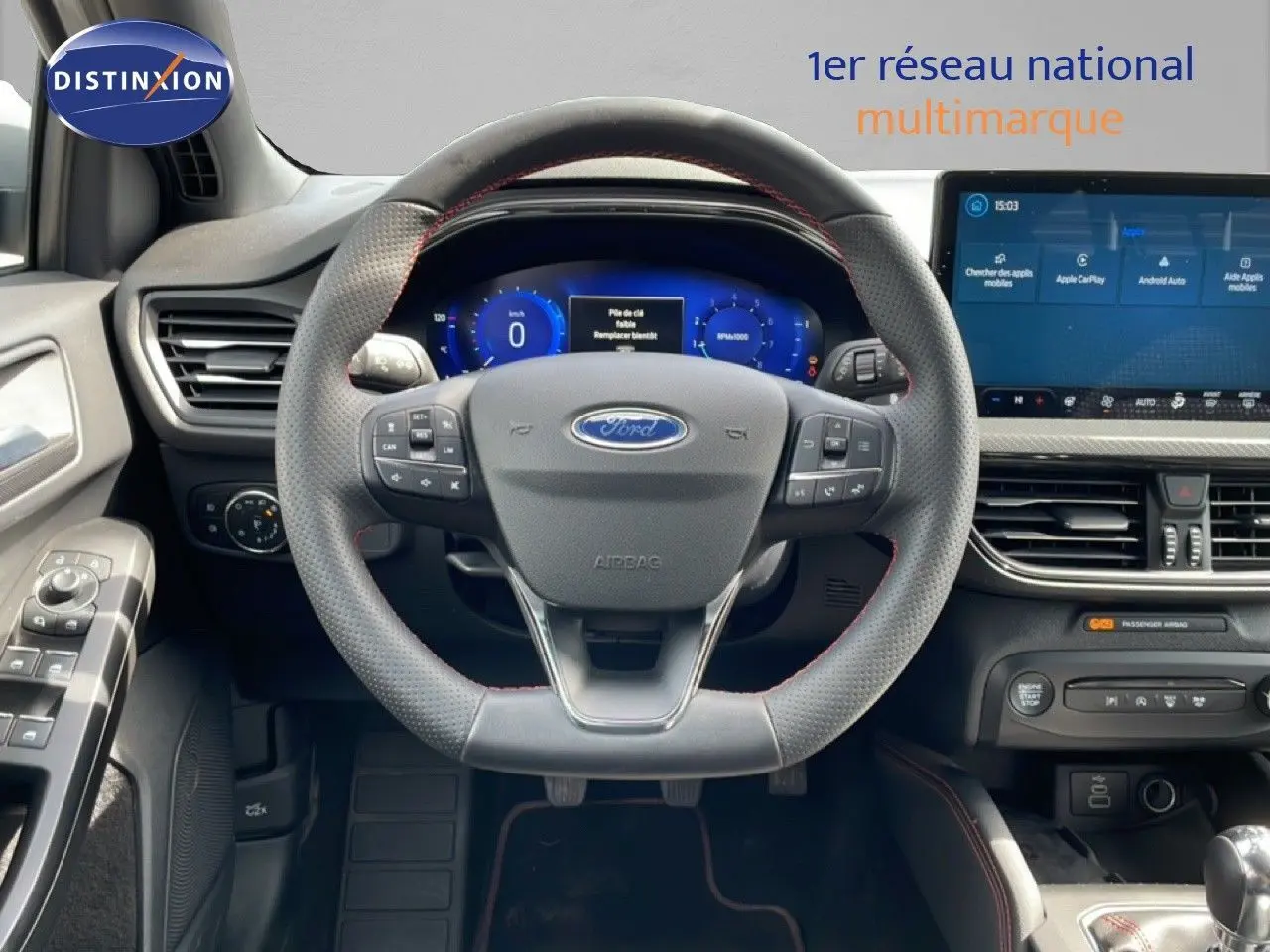 Vue intérieure centrée sur le volant perforé et l'écran tactile du tableau de bord de la Ford Focus SW gris lunaire.