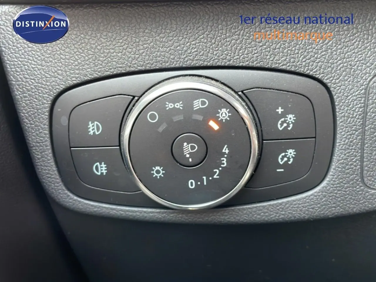 Gros plan sur la molette de réglage des phares du Ford Focus SW gris lunaire, avec commandes d’éclairage et régulateur de luminosité.