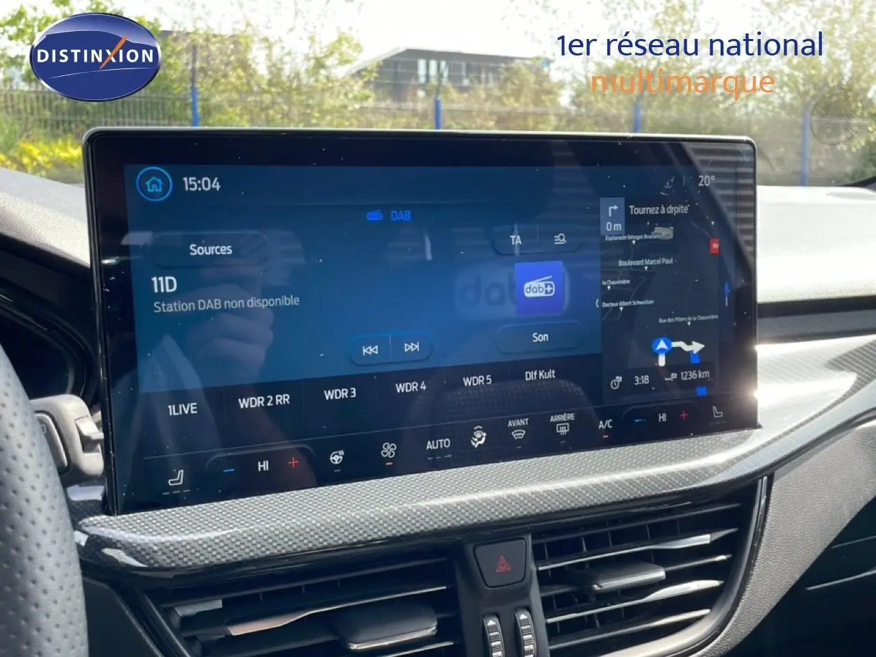 Vue rapprochée de l’écran tactile central de la Ford Focus SW 2023 gris lunaire, affichant la navigation et la radio numérique.